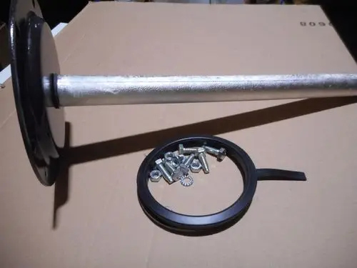 Remeha-Komponente mit einem Metallstab, einer schwarzen Flansche, einer Dichtung und mehreren Schrauben auf einem Kartonuntergrund.